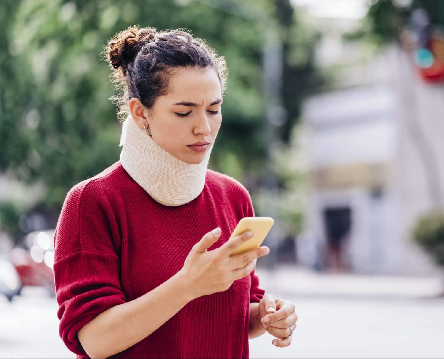 A woman in a next brace researching personal injury cases on her phone.