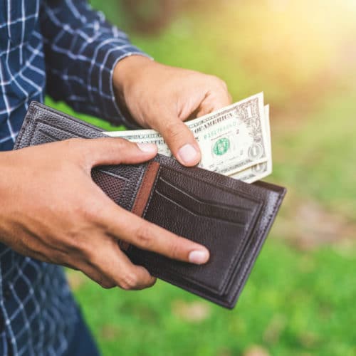 man putting money in wallet