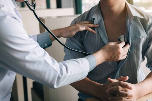 doctor is using a stethoscope listen to the heartbeat of the elderly patient.