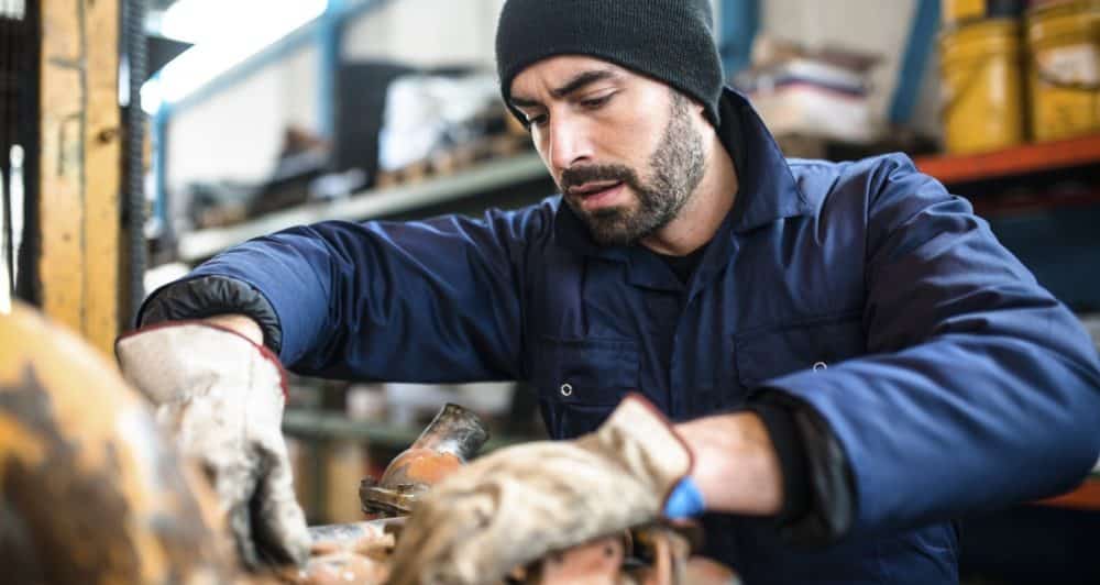 A mechanic working with a piece of machinery in a workshop.