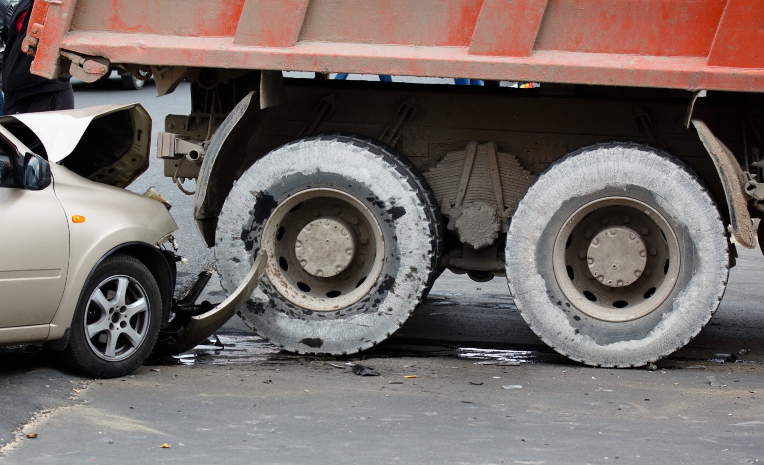 A small car has sustained severe damage after a collision with a dump truck in Boston.