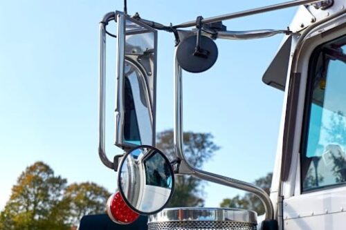 The side mirror of a tractor-trailer with large blind spots.
