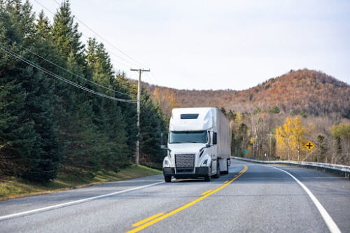 A Massachusetts big truck travels down a winding road.