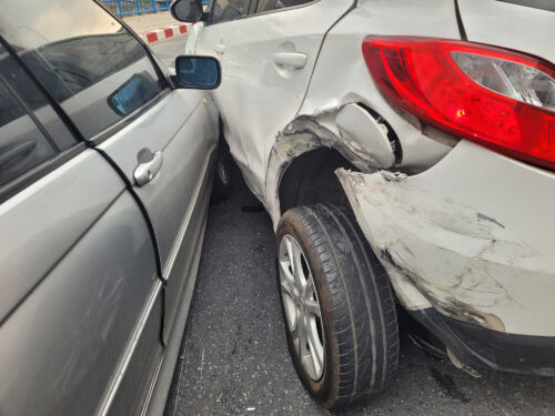Two cars are shown after a collision on a city street.